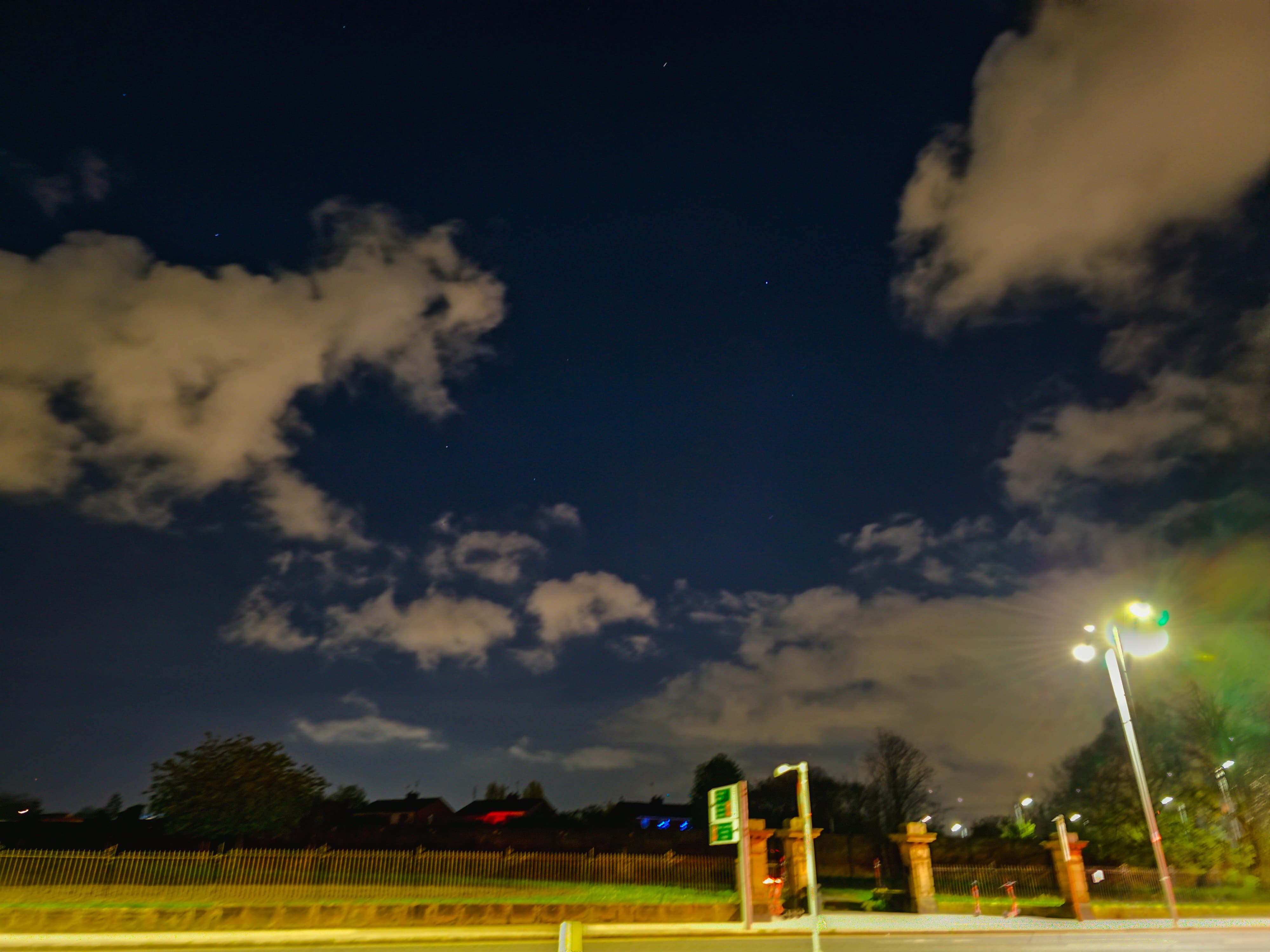 Clouds covering night sky with scattered lights near a park and houses in Liverpool