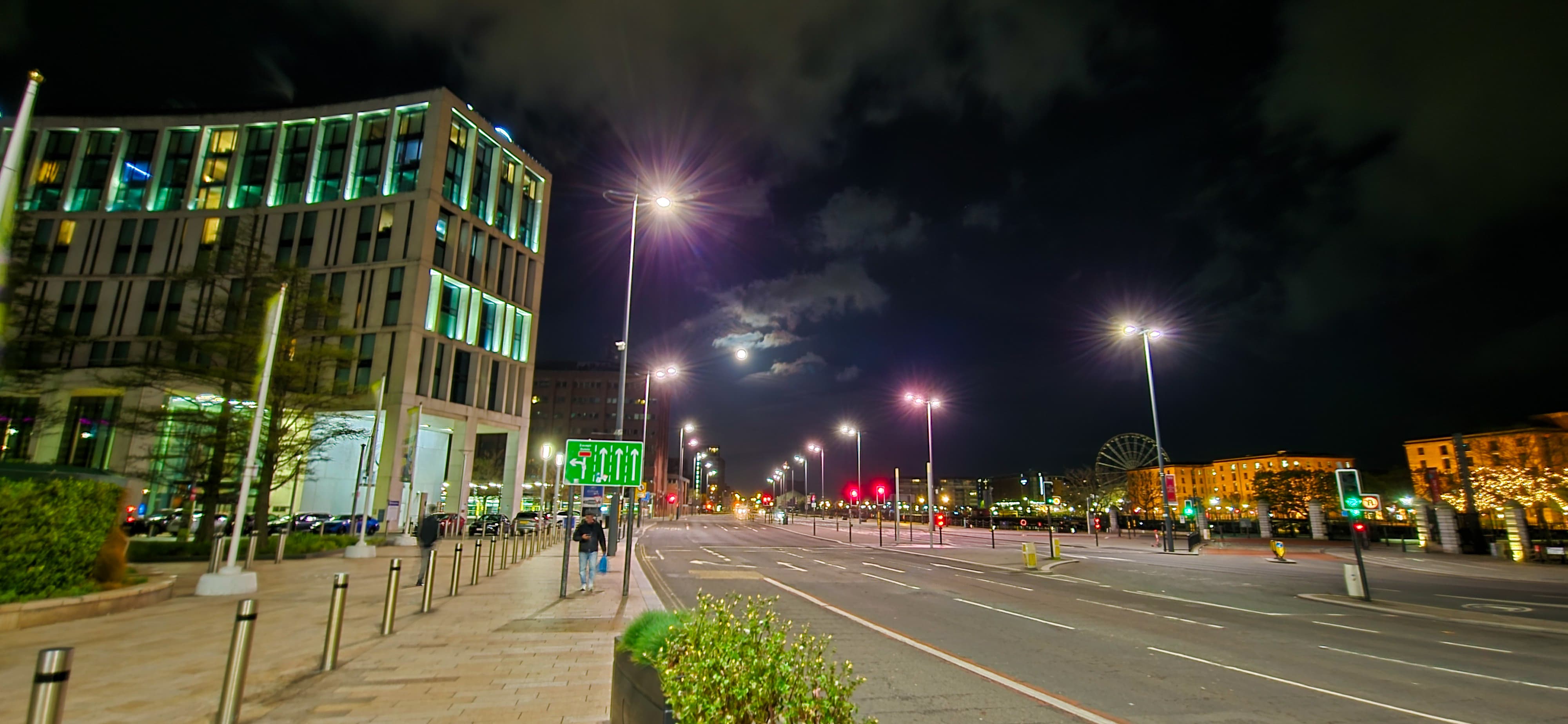 Night street view in Liverpool with tall buildings and the moon glowing behind clouds