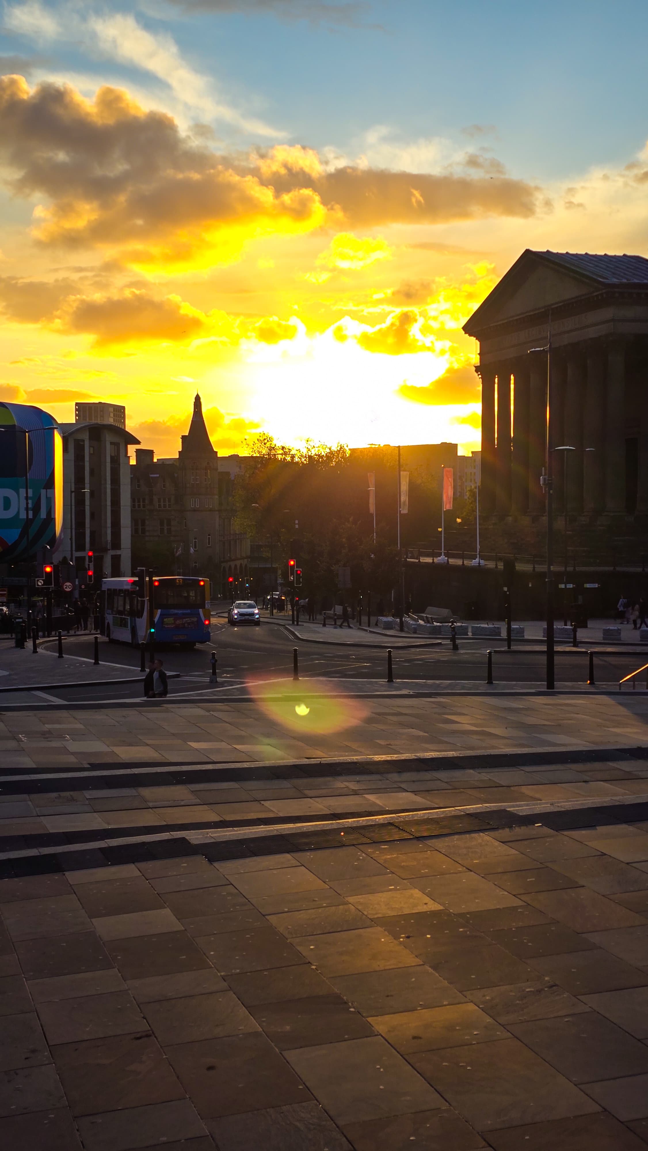 Golden sunset shining over a street in Liverpool with a bus and silhouetted buildings.