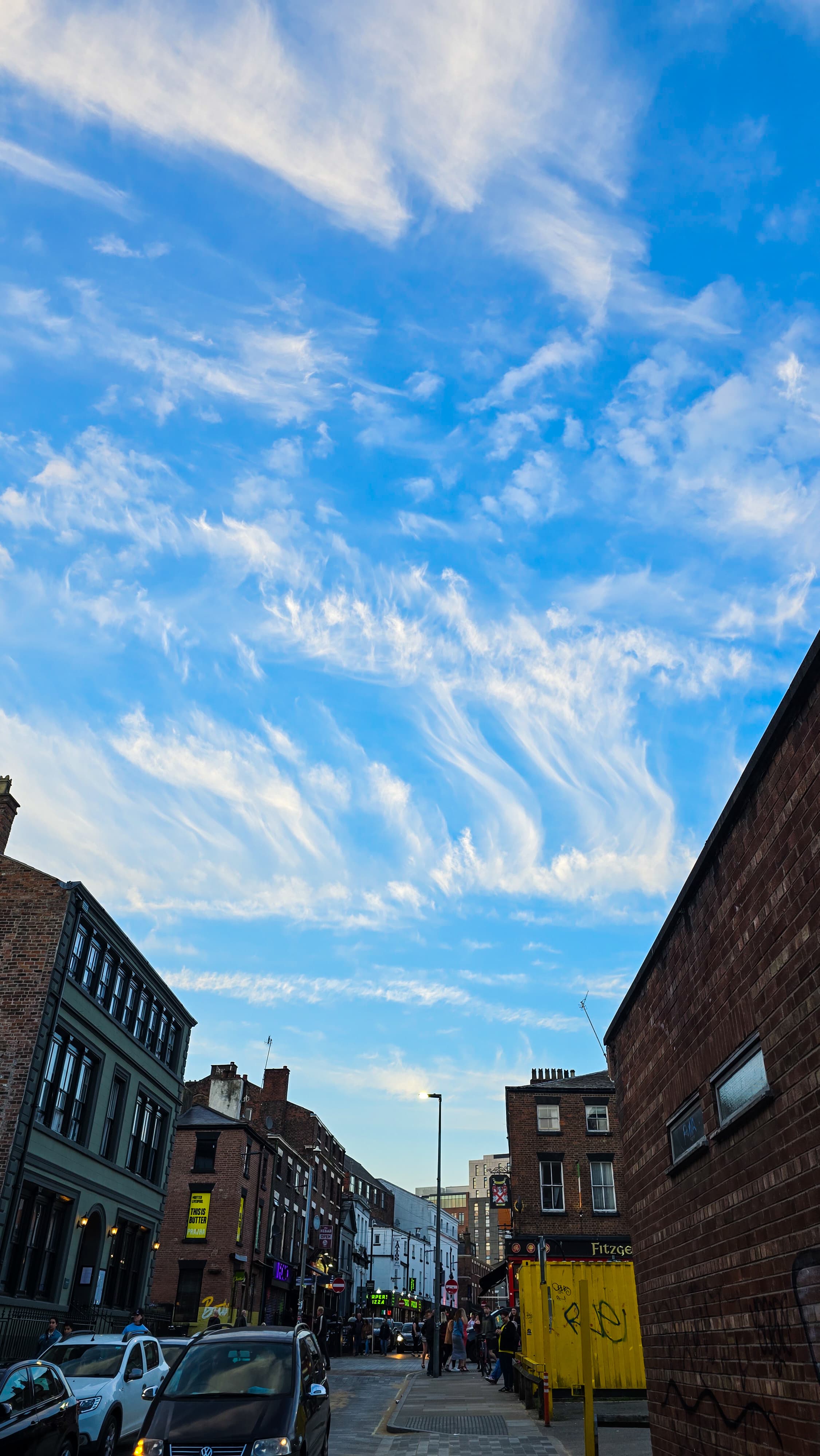 Evening view of a narrow street in Liverpool with dramatic swirling clouds in the sky